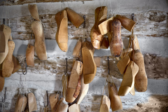 Various vintage wooden shoe lasts in a row on the old walls of the workshop