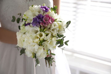 Bride holding beautiful bouquet with spring freesia flowers, closeup