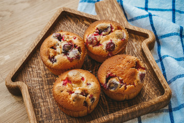 Muffins with cranberries and chocolate are beautifully laid out on the cutting Board, around the atmosphere of home and comfort, beautiful interior, natural wood, a Cup of tea