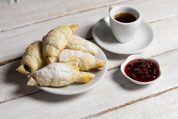 croissant, cup of coffee and raspberry jam on white wooden background