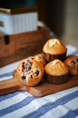Muffins with cranberries and chocolate are beautifully laid out on the cutting Board, around the atmosphere of home and comfort, beautiful interior, natural wood, a Cup of tea