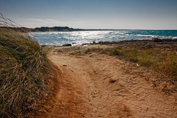 Dirt road of red earth leading to the sea.