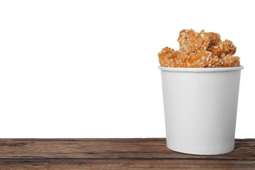 Bucket with yummy nuggets on wooden table against white background, space for text