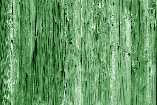 Wall of vertical wooden weathered planks in green tone.