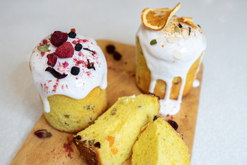 Various Easter cakes with white icing, decorated with berries and orange stand on a wooden board. Easter cutaway. Top view