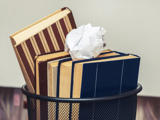 Books and crumpled paper in the bin. Books that do not read, low-grade literature