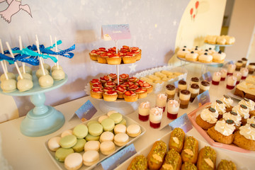 Delicious colored candy bar with cupcakes, macaroons, cake pops and other sweets