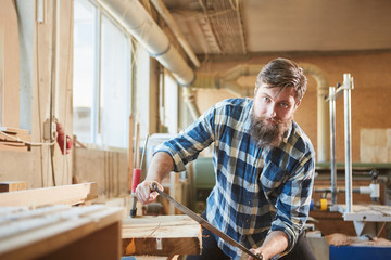 Hipster carpenter debarking wood