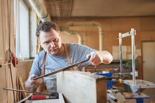 Carpenter debarks wood workpiece with pull knife