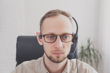 Young attractive man with a friendly smile wearing a headset for online communication as professional virtual client support or customer service