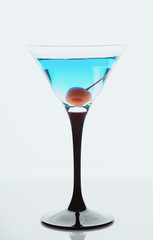 Blue martini cocktail with cherry on the rustic background. Selective focus. Shallow depth of field.