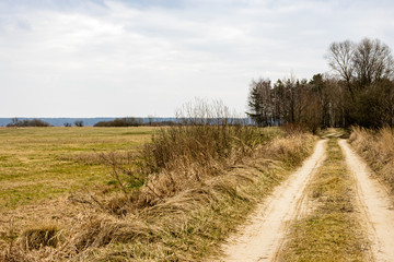Countryside straight dirt road, meadows and pastures. Rural landscape early spring day. Grady Polewne, Poland, Europe.