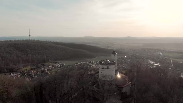 4k video flight around the remains of an old castle. Castle towers with spring forest. Sun glare. The ruins of Plesse, Germany.