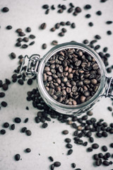 Fototapeta na wymiar Macro shot of a transparent jar filled with coffee beans in the center of the photo and coffee beans around the jar