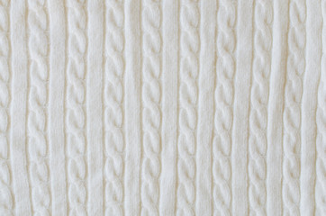 Beige knitted woolen background. Knitwear fabric texture.