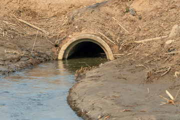 Naklejka premium Drainage system under the highway. Concrete pipe under the road. River