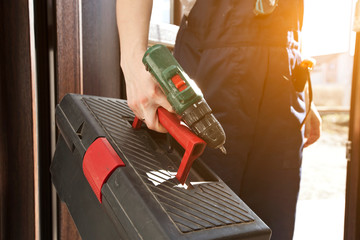 The woman repairer dressed in work uniform  is coming in the house with toolbox and other equipment in his hand