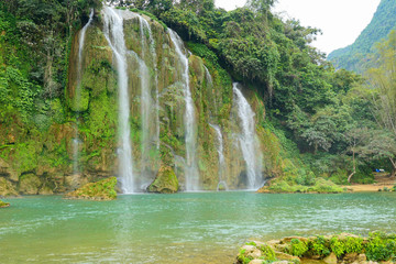Full of water huge waterfall near the green forest with green trees in mountains