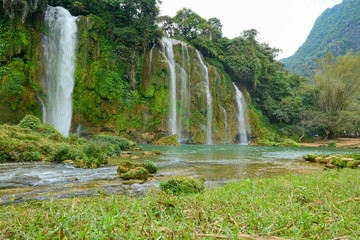 Full of water huge waterfall near the green forest with green trees in mountains