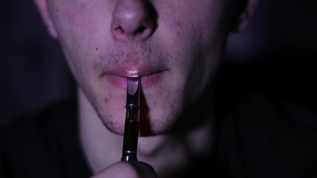 Close up on a young males mouth while vaping