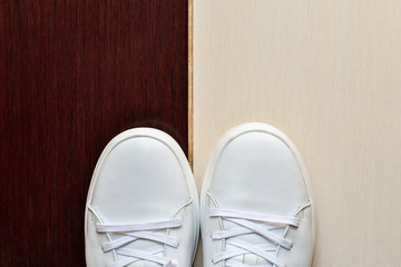 Obraz na płótnie Canvas White casual sneakers on light beige and brown tile background. Copy space.