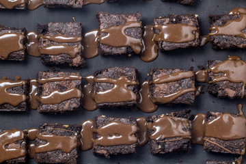 Chocolate cake brownie squares dribbled with chocolate ganache sauce isolated on black