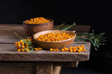 Sea buckthorn in the plate and around Sea buckthorn berries on wooden table