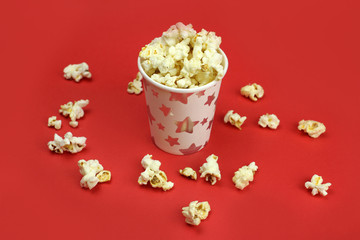caramel popcorn in a paper Cup and scattered on a bright red background