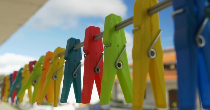 Colorful clothespins hanging against a blue sky in a sunny day.
