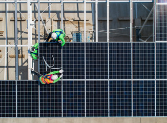 top view worker installing a solar cell on the factory roof.