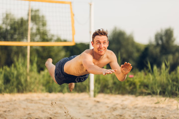 Junger Mann am Hechten beim Beachvolleyball