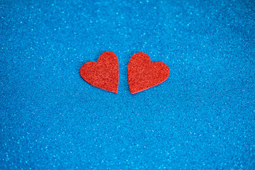 Obraz premium Two red glitter hearts on shiny blue background