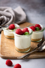 cheesecake in a glass decorated with raspberries and mint on a gray background