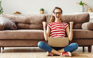 Glad woman celebrating good news while working on laptop at home