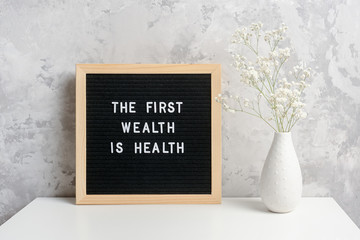 The first wealth is health. Motivational quote on letter board and bouquet of flowers gypsophila in...