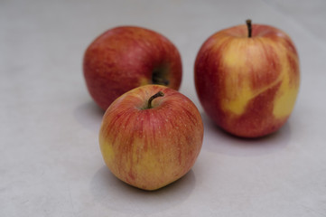 Three red apples on a white background, apples on a white table, fresh apples in the kitchen
