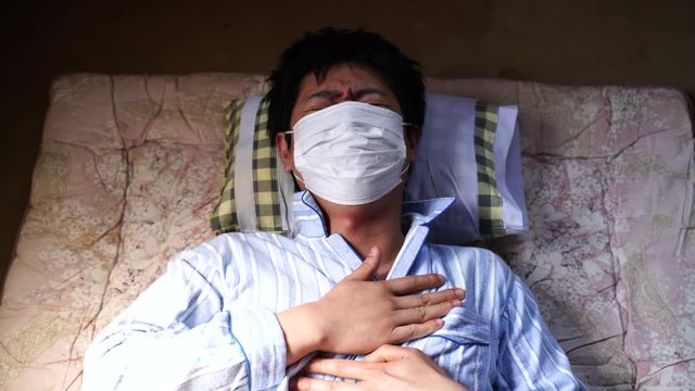 病気・寝床で咳をするマスクの男性　新型コロナウイルス感染症　イメージ