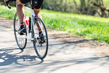 Ausschnitt Räder und Beine eines Fahrradfahrers auf seinem Rennrad unterwegs in der Natur