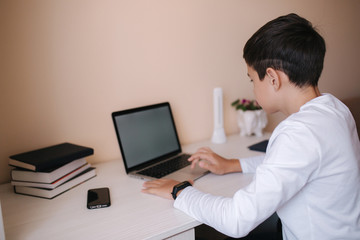 Schoolboy play online games at home while study on quarantine. Mockup of laptop