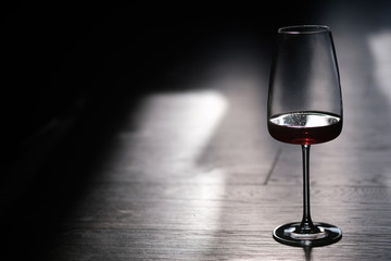 Beautiful unfinished glass glass of red wine on a dark floor