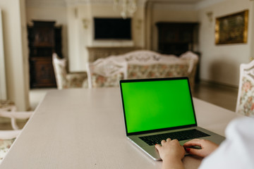 Fototapeta premium Woman using laptop with green screen. Woman's hands typing on a laptop keyboard. Business, communication, freelance and internet concept