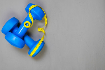 dumbbell and centimeter on a light background