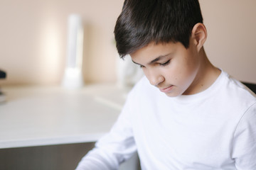 Young boy sitting by the desk and read the book. Study at home during quarantine