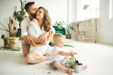 Obraz na płótnie Canvas Happy family working at home. Transplanting plants with their child