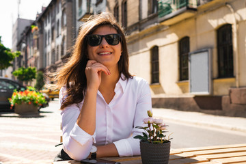 Beautiful young woman sitting outdoors in the city and smiling