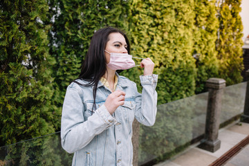 Fototapeta premium smiling young woman removes medical mask from face. termination of quarantine, coronavirus. Woman protecting from coronavirus. Covid-19. happy time, fresh air