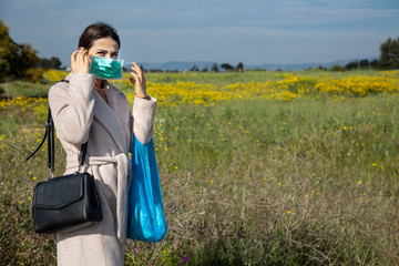 Ragazza mora vestita casual  con un cappotto chiaro, passeggia con una busta per la spesa blu e una...