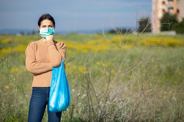 Ragazza mora vestita casual , con una busta per la spesa blu e una mascherina protettiva  su sfondo...