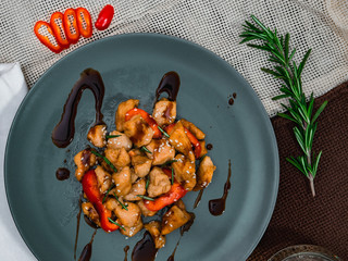 Chicken with soy sauce and chopsticks on blue plate. Chinese dish, spicy lunch.
