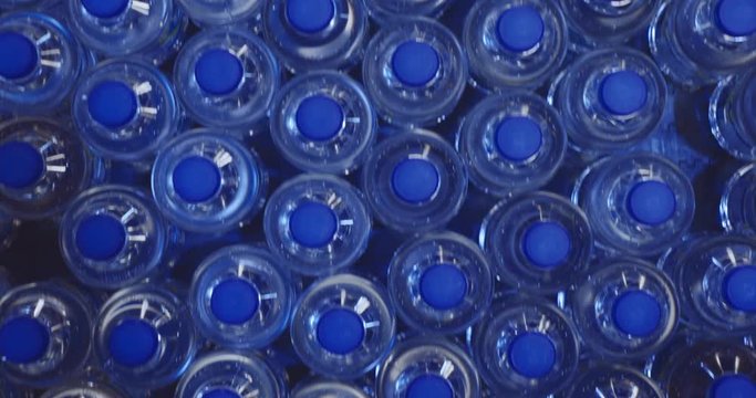 Plastic bottles moving on a conveyer belt in a production factory. Top view.